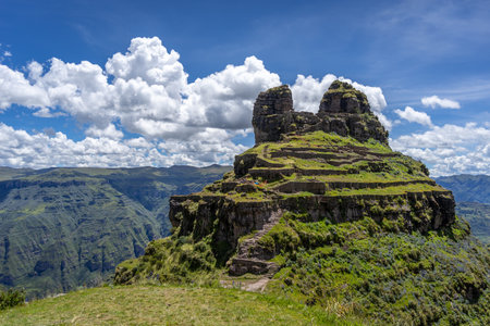 The archaeological site of Waqrapukara in Peru features terraced stone ruins on a rugged mountain peak, offering stunning views of the surrounding Andean landscapeの写真素材