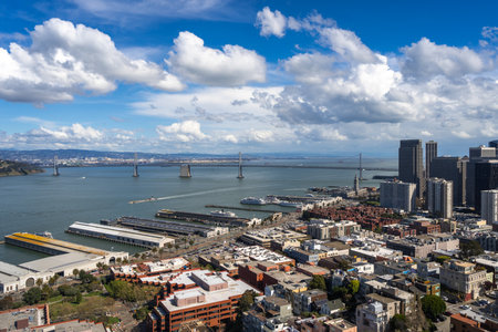 Aerial view of San Franciscoâs downtown with modern skyscrapers and the Bay Bridge under a blue sky with scattered cloudsの写真素材