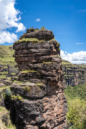 Ancient stone walls and terraces of Waqrapukara blend into the surrounding green mountains, highlighting Inca engineering in this remote Andean landscape under a bright skyの写真素材