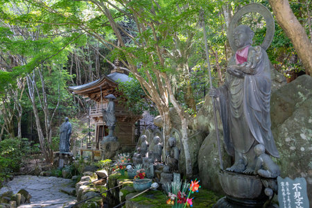 Bronze monk statues line a moss-covered chozuya fountain in Daisho-in Temple, creating a peaceful...