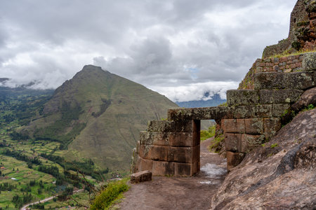 The Inca archaeological site of Pisac sits atop a lush green valley surrounded by misty Andean peaks. Stone terraces and ancient walls blend with the natural landscape, offering a glimpse into Peruâs rich history and breathtaking sceneryの写真素材