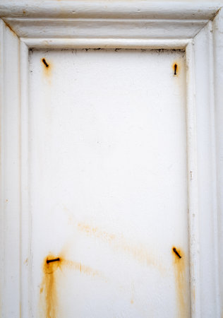 A close-up of a white wooden frame with rusty nails and peeling paint. The surface is aged, weathered, and marked by corrosion and natural wearの写真素材