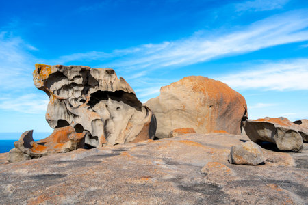 Remarkable Rocks in Flinders Chase National Park, Kangaroo Island, Australia, feature unique granite formations shaped by wind and sea erosion, covered in vibrant orange lichen, creating a stunning contrast against the deep blue oceanの写真素材
