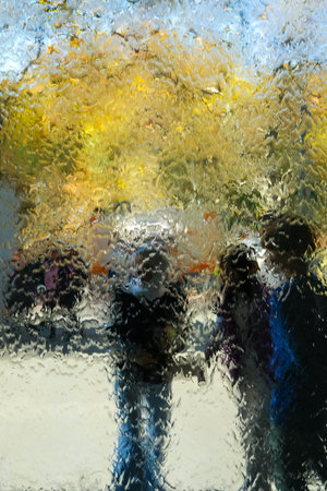 The water wall at the National Gallery of Victoria in Melbourne, Australia, distorts the view of people and trees behind it. The cascading water creates a unique, abstract effect, blending colors and shapes into a fluid, artistic compositionの写真素材