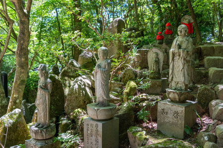 Peaceful moss-covered statue of a praying monk nestled in the quiet greenery of Mitaki-Dera temple garden in Hiroshima, Japanの写真素材