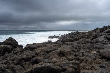 The peaceful Playa Loberia beach in San Cristobal, Galapagos, with its rocky shoreline and dark...