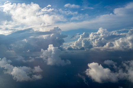 Majestic clouds illuminated by the sun create a dramatic sky viewed from above. The bright sunlight...