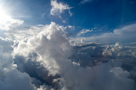 Majestic clouds illuminated by the sun create a dramatic sky viewed from above. The bright sunlight...