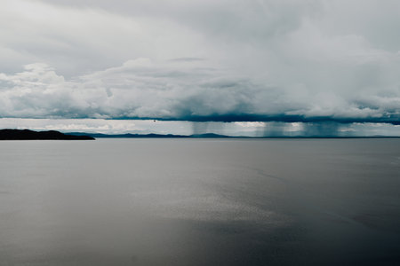 Expansive view of Lake Titicaca from Taquile Island, with calm waters reflecting a dramatic sky...