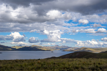 Lake Lagunillas in Peru is surrounded by rolling hills and grasslands, with dark storm clouds above...