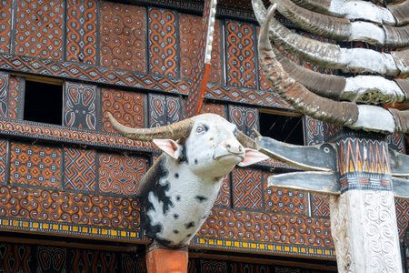 Carved wooden panels and a buffalo head sculpture adorn a traditional Toraja house, symbolizing...