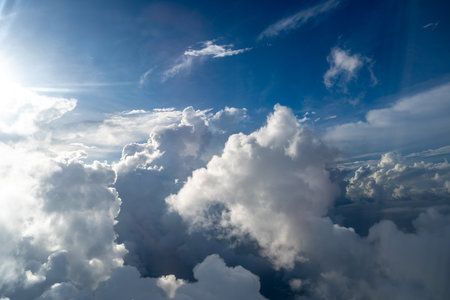 Majestic clouds illuminated by the sun create a dramatic sky viewed from above. The bright sunlight...