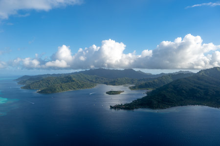 Tahaa island in French Polynesia, seen from above, reveals a turquoise lagoon, coral reef, and lush...