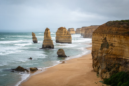 The Twelve Apostles, iconic limestone stacks along the Great Ocean Road, Australia, rise dramatically from the ocean, surrounded by rugged cliffs and golden sandy beachesの写真素材