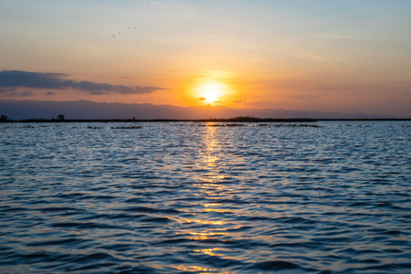 Calm waters of Lake Tempe reflect the glowing sunset, illuminating the Sulawesi horizon in Indonesia...
