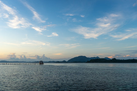 A peaceful sunset over the long wooden pier on Bolilanga Island, Togian archipelago, Sulawesi, Indonesia, with calm waters and pastel skiesの写真素材