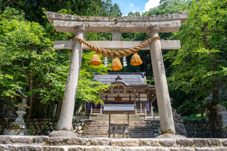 Stone torii gate adorned with sacred rope and paper shide, marking the entrance to Shirakawa Hachiman Shrine in the village of Shirakawa-goの写真素材