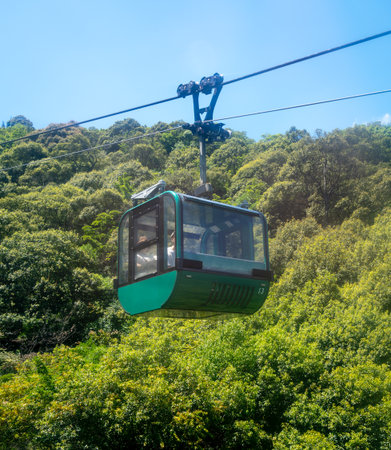A gondola from the Miyajima Ropeway moves over the lush green mount Misen in Itsukushima Island, offering scenic views near Hiroshima, Japanの写真素材