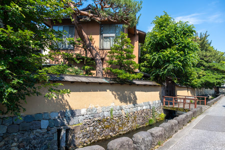 A peaceful street lined with earthen walls and a stone canal in the historic samurai neighborhood of Nagamachi District, Kanazawa, Japanの写真素材
