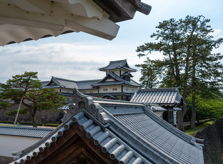 Traditional Japanese architecture of Kanazawa Castle with stone walls, surrounded by greenery and blue sky in Japanの写真素材