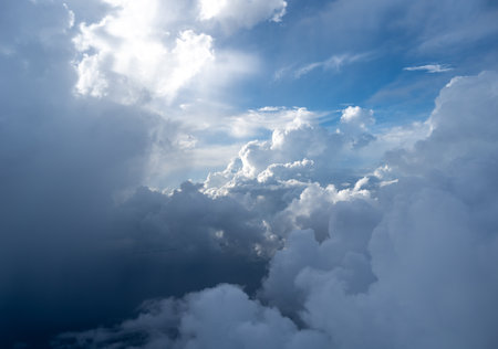 Majestic clouds illuminated by the sun create a dramatic sky viewed from above. The bright sunlight...