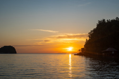 Golden sunset over Bolilanga Island in the Togian archipelago, Sulawesi, Indonesia, with glowing...