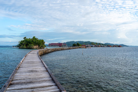 A long wooden jetty stretches over turquoise waters towards the traditional Bajo village of Pulau Papan, on Malenge Island, in the Togian Archipelagoの写真素材