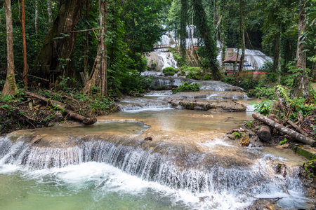 The Saluopa waterfall cascades down mossy rocks surrounded by lush tropical forest near Tentena, Sulawesi, Indonesia, creating a beautiful natural sceneの写真素材