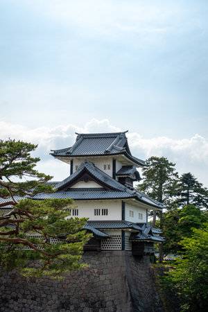 Traditional Japanese architecture of Kanazawa Castle with stone walls, surrounded by greenery and blue sky in Japanの写真素材