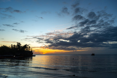 Golden sunset light reflects on the calm sea at Lia beach, Waleakodi Island, Togian archipelago, Sulawesi, Indonesia, creating a peaceful tropical sceneの写真素材