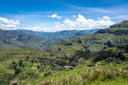 The Waqrapukara site in Peru features dramatic rock formations, green valleys, and steep cliffs, offering breathtaking views of the Andean highlands under a bright blue skyの写真素材