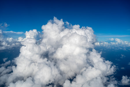 Majestic white clouds float above the deep blue Pacific Ocean, captured from an airplane flying over...