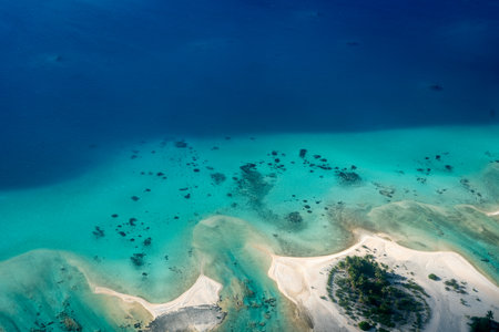 A breathtaking aerial view of a motu in Tikehau Atoll, French Polynesia. The turquoise waters contrast beautifully with the sandy islets and lush green vegetationの写真素材