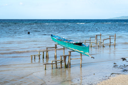 A traditional canoe rests on wooden stilts by the shore of Malenge Island in the stunning Togian Archipelago, Sulawesi, Indonesiaの写真素材
