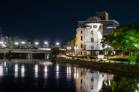 The Genbaku Dome stands silently lit along the river in Hiroshima Peace Memorial Park, Japan, symbolizing resilience and remembrance after unimaginable destructionの写真素材