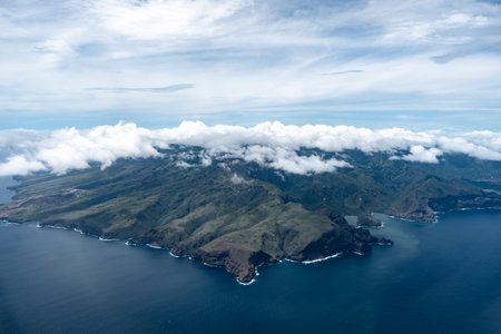 Nuku Hiva, the largest island in the Marquesas, features rugged green mountains, dramatic cliffs, and a remote coastline, partially covered by misty clouds over the Pacific Ocean. French Polynesiaの写真素材
