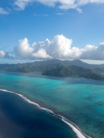 Tahaa island in French Polynesia, seen from above, reveals a turquoise lagoon, coral reef, and lush mountains. The vibrant ocean colors contrast with the deep blue Pacificの写真素材