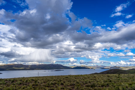 Lake Lagunillas in Peru is surrounded by rolling hills and grasslands, with dark storm clouds above...