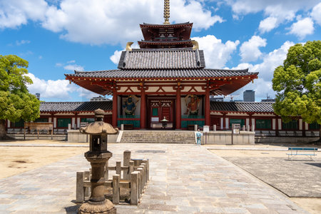 A man prays in front of the main gate of Shitenno-ji Temple in Osaka, where traditional architecture and spiritual atmosphere meet under a bright skyの写真素材