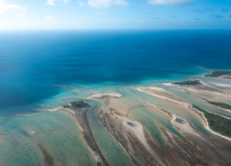 A breathtaking aerial view of a motu in Tikehau Atoll, French Polynesia. The turquoise waters contrast beautifully with the sandy islets and lush green vegetationの写真素材