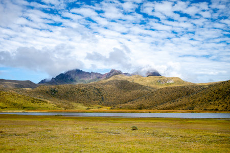 A peaceful landscape showcasing the mountains surrounding the Cotopaxi volcano in Ecuador, with a small lake under a vibrant skyの写真素材