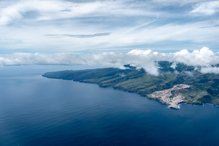 Nuku Hiva, the largest island in the Marquesas, features rugged green mountains, dramatic cliffs, and a remote coastline, partially covered by misty clouds over the Pacific Ocean. French Polynesiaの写真素材