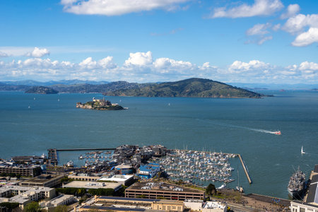 Aerial view of San Francisco Bay with Alcatraz Island, sailboats, and a marina under a bright blue sky with scattered clouds in Californiaの写真素材