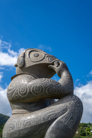 A modern stone tiki statue with intricate carvings, standing in Atuona Bay, Hiva Oa, Marquesas Islands, French Polynesia. A symbol of Polynesian heritage and cultureの写真素材