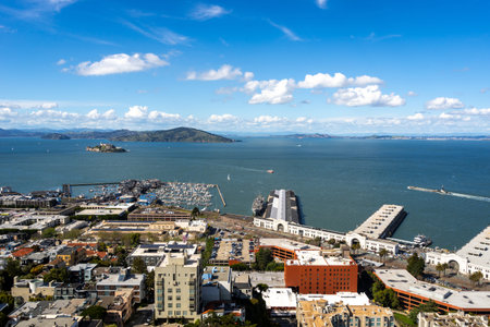 Aerial view of San Francisco Bay with Alcatraz Island, sailboats, and a marina under a bright blue...