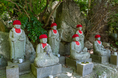 In a peaceful forest at Mitaki-Dera temple in Hiroshima, Japan. Jizo Bosatsu statues wear red...