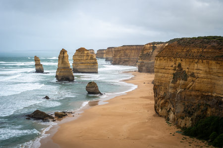 The Twelve Apostles, iconic limestone stacks along the Great Ocean Road, Australia, rise dramatically from the ocean, surrounded by rugged cliffs and golden sandy beachesの写真素材