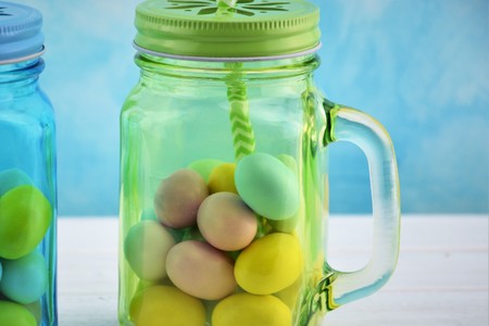 Sky-blue and green transparent glass jars with colored Easter eggs