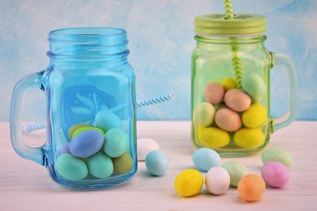 Sky-blue and green transparent glass jars with colored Easter eggsの写真素材