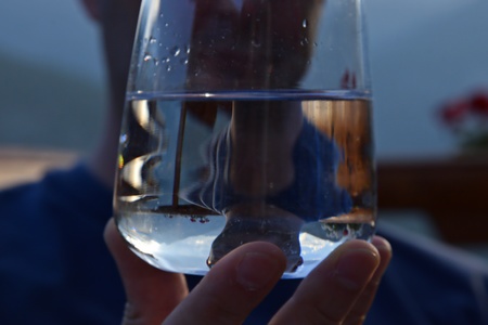 Man behind a glass of water in his handの写真素材